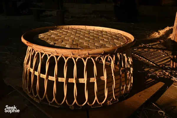 Round woven bamboo structure with curved slats on a workshop floor in Xishuangbanna, highlighting traditional tea-region crafts