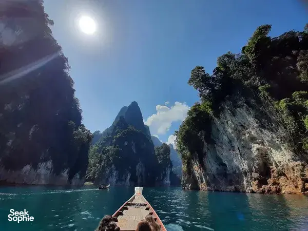 Boat deck with a drink bottle under bright sun, cruising through narrow karst bays in Khao Sok, Cheow Lan Lake