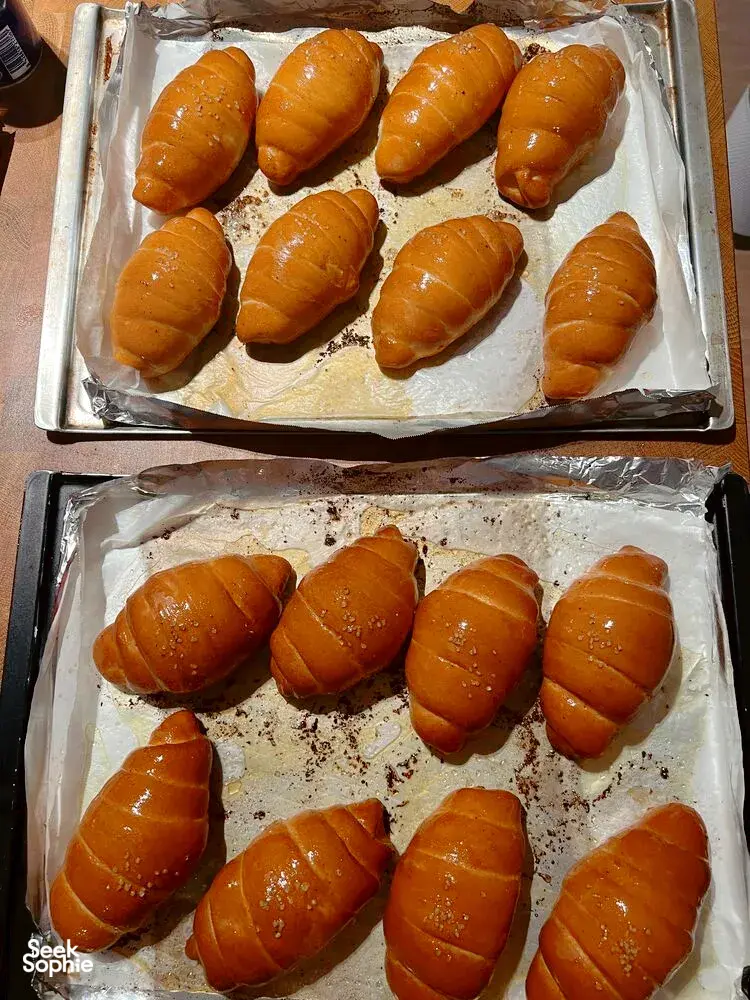 Golden shio pan rolls lined on baking trays at a The Daily Staples bread-making class in Singapore, ready to cool after baking