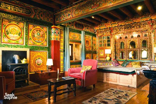 Ornately decorated Tibetan-style room inside Ferme Liotard in Shangri-La, with vivid wall hangings, cushioned chairs and lamps
