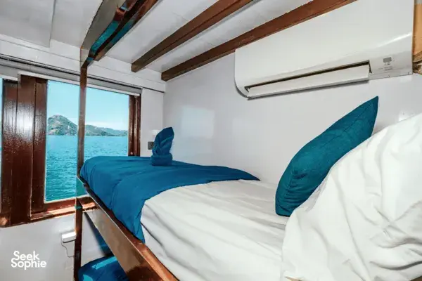 Sleek white phinisi cabin with bunk beds and sea view on a 3D2N Komodo adventure with La Famille in Labuan Bajo