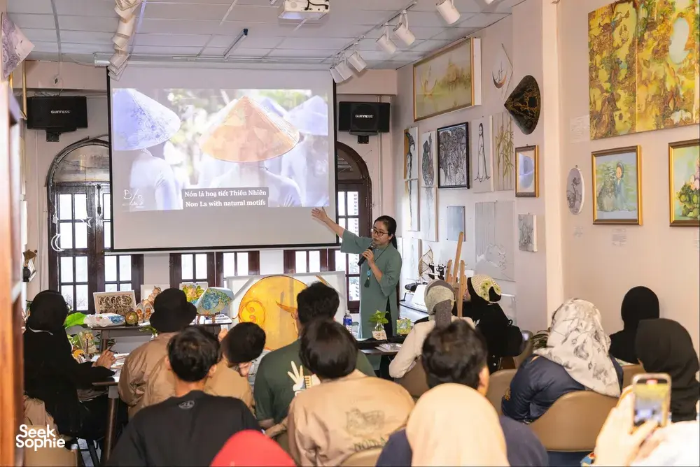 Workshop room in Ho Chi Minh City with an audience facing the presenter and a projector screen showing Vietnamese art designs