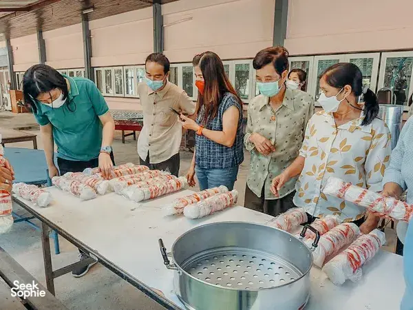 Masked participants preparing fabric bundles on tables with a large dye pot during Dip-Dye By Noo’s Chiang Mai eco-print jamming