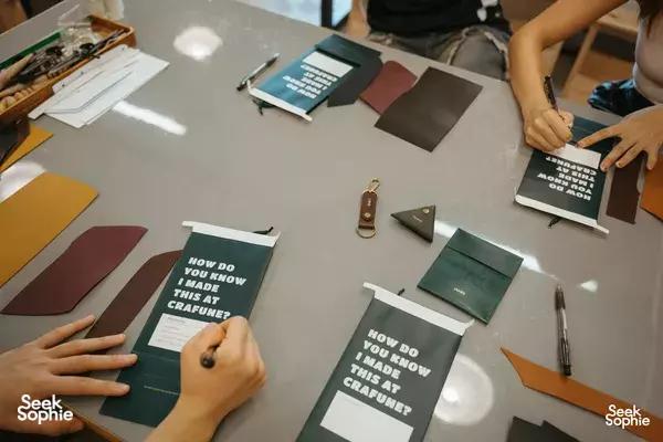 Crafune leathercraft class in Singapore: hands arrange coloured leather panels on the table with tools — workshops in Singapore