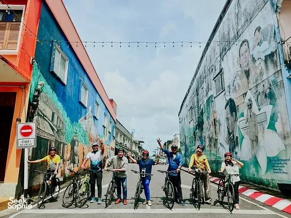 Helmed cyclists lined up with bicycles along a painted alley in Takua Pa Old Town, Khao Lak during a private cycling trip