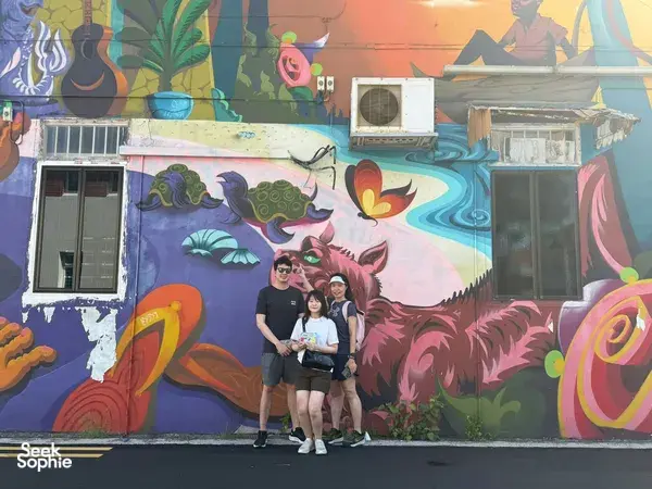 Team members posing in front of a dragon mural in Katong-Joo Chiat on a Monopoly-style team-building trail through Singapore hidden gems.