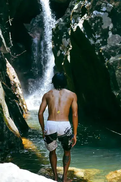 Nguyen Tours Hoi An secret waterfall on a motorbike adventure, swimmer standing in the canyon pool with back to the camera