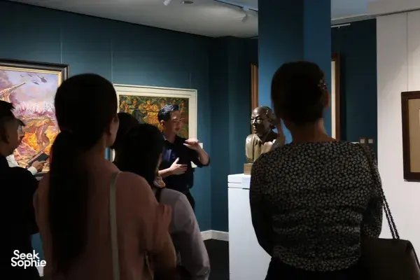 Pemandu menjelaskan lukisan Vietnam kepada pengunjung dalam tur yang dipandu ahli di Museum Seni Quang San, Ho Chi Minh City
