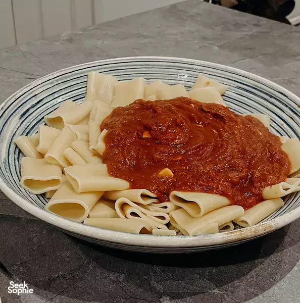 Fettuccine with rich tomato sauce served in a blue-striped bowl for private dining Singapore at a Peranakan shophouse