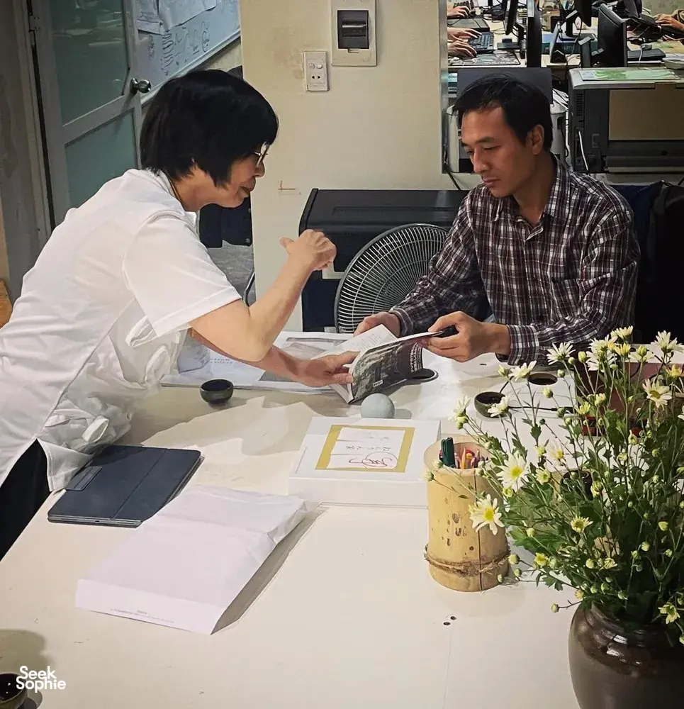 Two people reviewing papers at a meeting table, preparing a host-led Hanoi collective housing walk