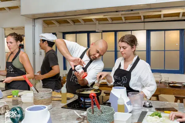 Gili Islands cooking class in Lombok: guests pour and stir ingredients at the stove, learning how to make peanut sauce