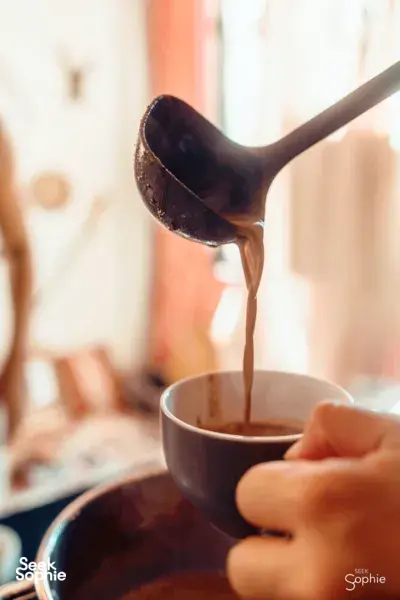 Melting chocolate poured into a bowl as hands stir during a bean-to-bar chocolate-making workshop in Singapore