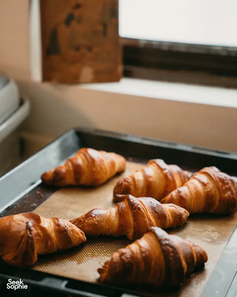 Tray of golden croissants resting on a baking sheet in an oven during a French croissant baking session in Singapore