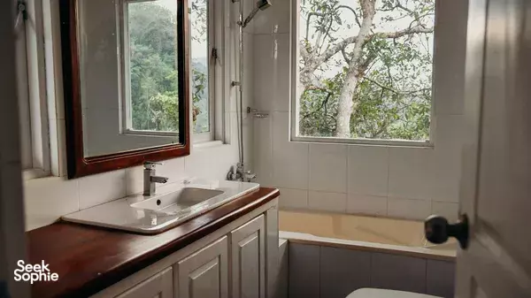 Bathroom wash area with a countertop sink and large window overlooking greenery at Old Frankland Tea Estate in Kandy