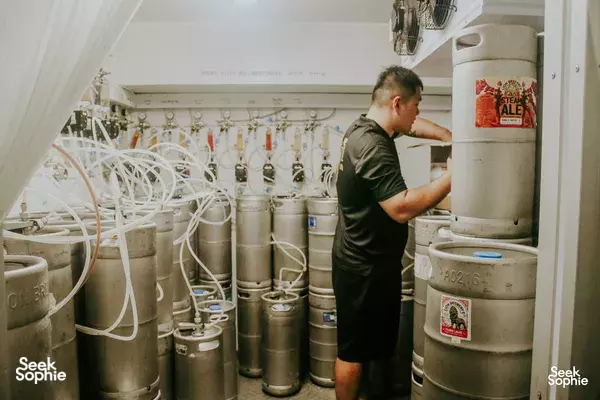 Lion Brewery Co Brewpub Tour in Singapore: guide checking fermentation tanks beside branded kegs in the brewery room