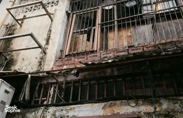Fasad berjendela dengan jeruji, plester mengelupas, dan rel berkarat, dari Behind Jalan Besar’s Doors oleh Hidden Heritage dalam hidden gems Singapura