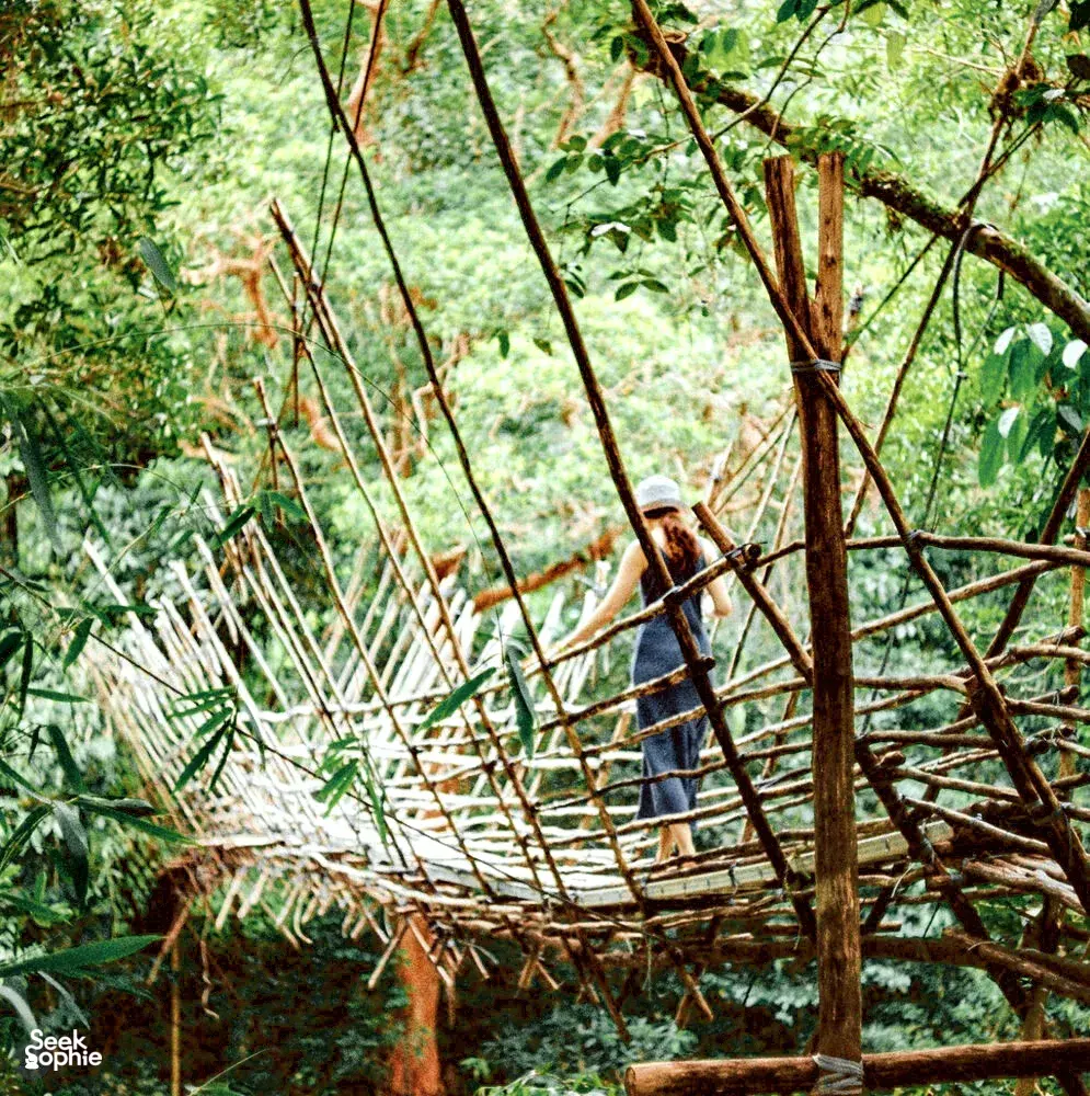 Ngapuh Homestead builder in a hat working among bamboo and branches in the forest, rainforest tones near Kuching
