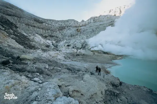 Hikers on the rocky rim of Mt Ijen at sunrise, watching the blue crater lake vents, on a 3D2N trip from Banyuwangi