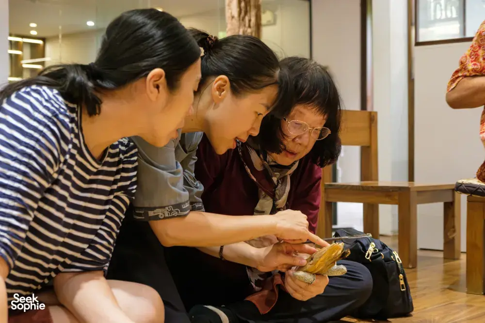 Guests lean over a table to examine golden agarwood samples together during a hands-on rare agarwood tour in Hanoi