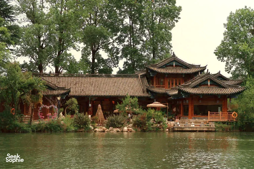 Traditional Naxi wooden buildings and garden courtyard steps beside a lake in Shuhe Ancient Town, Lijiang