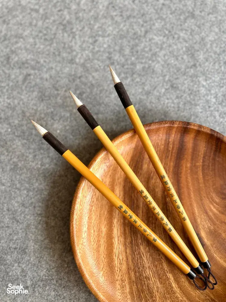 Chinese calligraphy brushes resting in a wooden dish for 'Write Your Own Blessing' in Singapore—workshops in Singapore