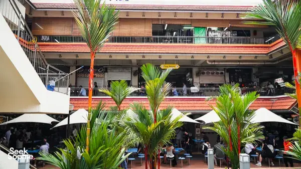 Courtyard hawker centre in Singapore with shared dining tables and open-air seating, part of Jenny Dorsey’s stories — Singapore hidden gems