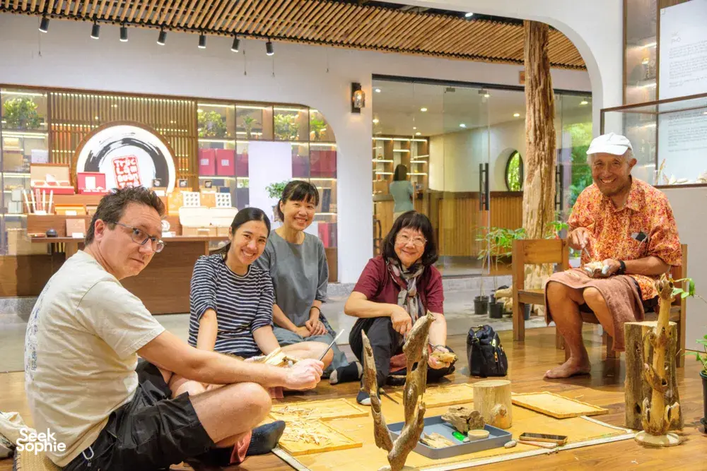 Up Travel Vietnam host-led tour in Hanoi where travellers examine carved agarwood pieces in a traditional workshop