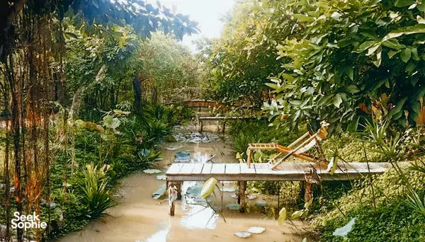 Luxury eco homestay grounds at Bamboo Eco Village in Cần Thơ, Mekong Delta—shaded lily pond with wooden platforms and deck chairs