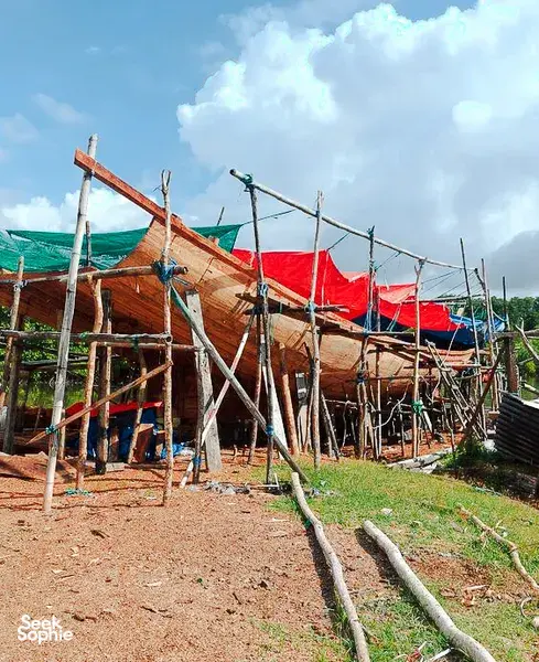 Boatside wooden vessel with red sail awning during a hidden mangroves and village visit day trip, Labuan Bajo