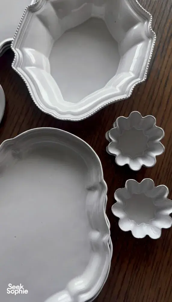 Antique-style scalloped ceramic plates and serving platters on a wooden table at Ina Atelier workshops in Singapore