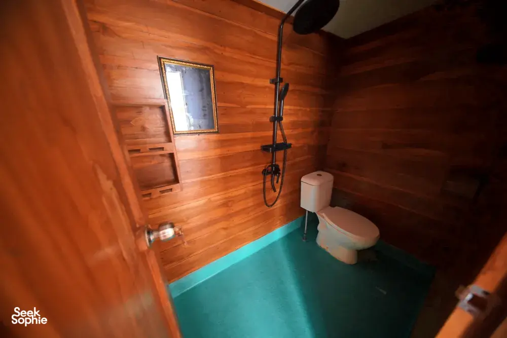 Travass Life 3D2N join-in Komodo trip cabin bathroom with toilet, hand shower and wooden walls, Labuan Bajo