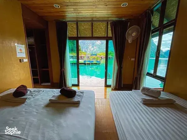 Glamping room with two beds and open curtains facing the lake for a peaceful Khao Sok stay at Cheow Lan Lake