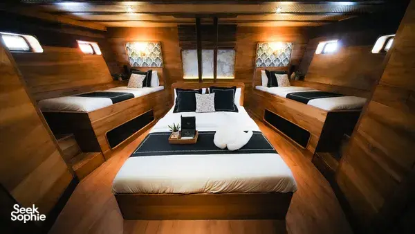 Twin cabin interior on Angelica Liveaboard with neatly made beds and a central table, onboard a 3D2N luxe Komodo cruise in Labuan Bajo
