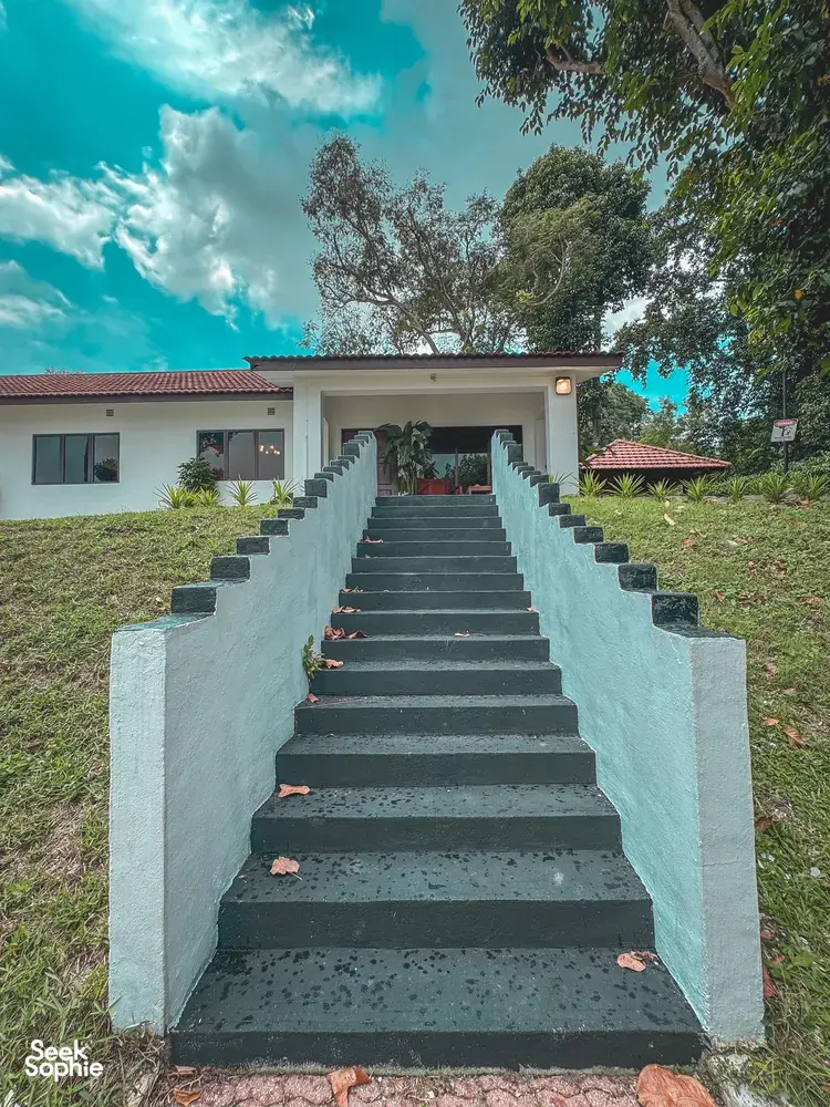 Stairway to a white bungalow at a Singapore 2D1N farmstay by the sea, set among greenery and hedges
