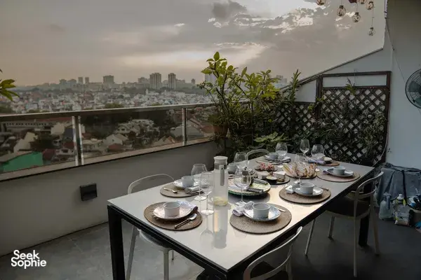 Rooftop table set for sunset drinks with French bites, overlooking a Singapore city skyline from a cosy loft for private dining Singapore