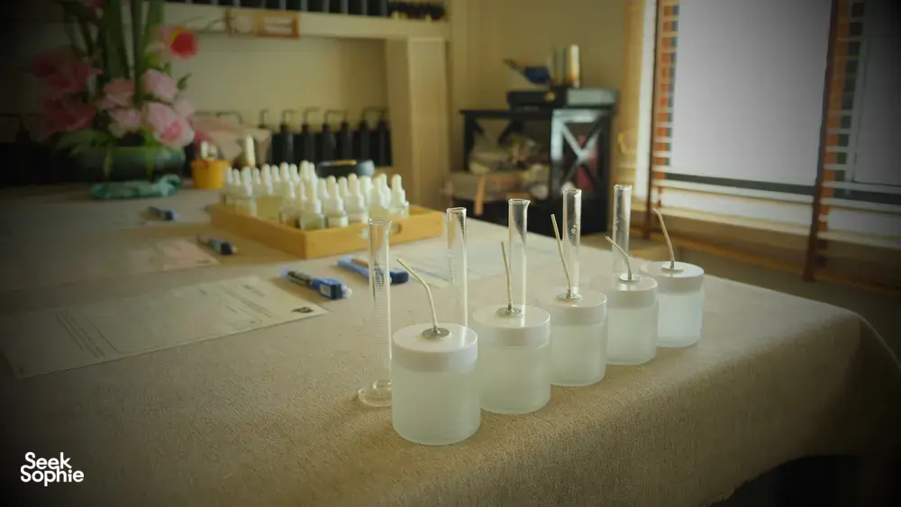 White coco-soy candle jars lined on a table in Singapore, ready for custom scent blending at a perfume workshop