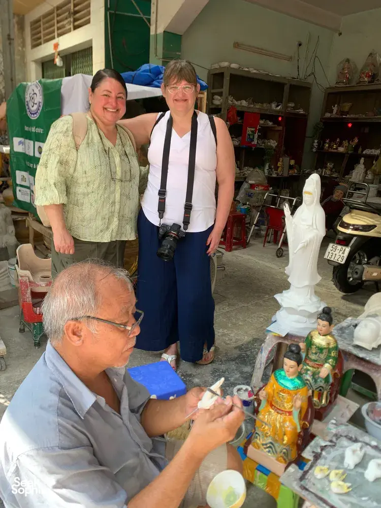 Tour visitors browse a stall of ornate white statues and figurines in a craft market in Ho Chi Minh City with Viet Awesome Tours