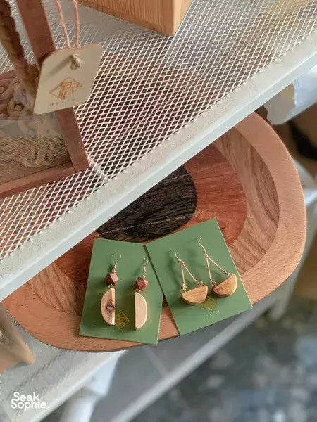 Handmade wooden earrings on green cards beside a round wooden tray in a Singapore woodworking jewellery workshop — workshops in Singapore