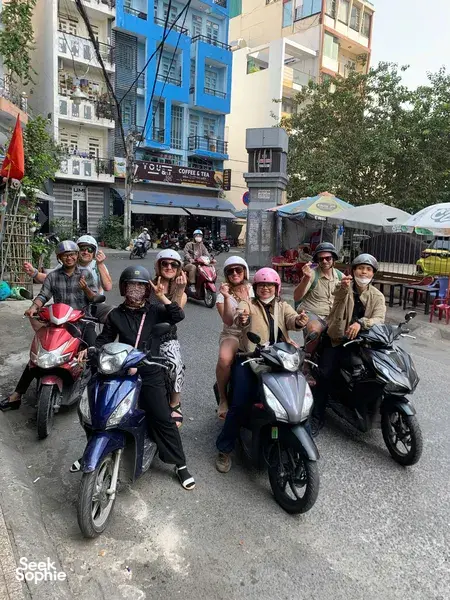 Motorbike group posing for a guide on a busy street in Ho Chi Minh City during the Saigon hidden craft alleys tour