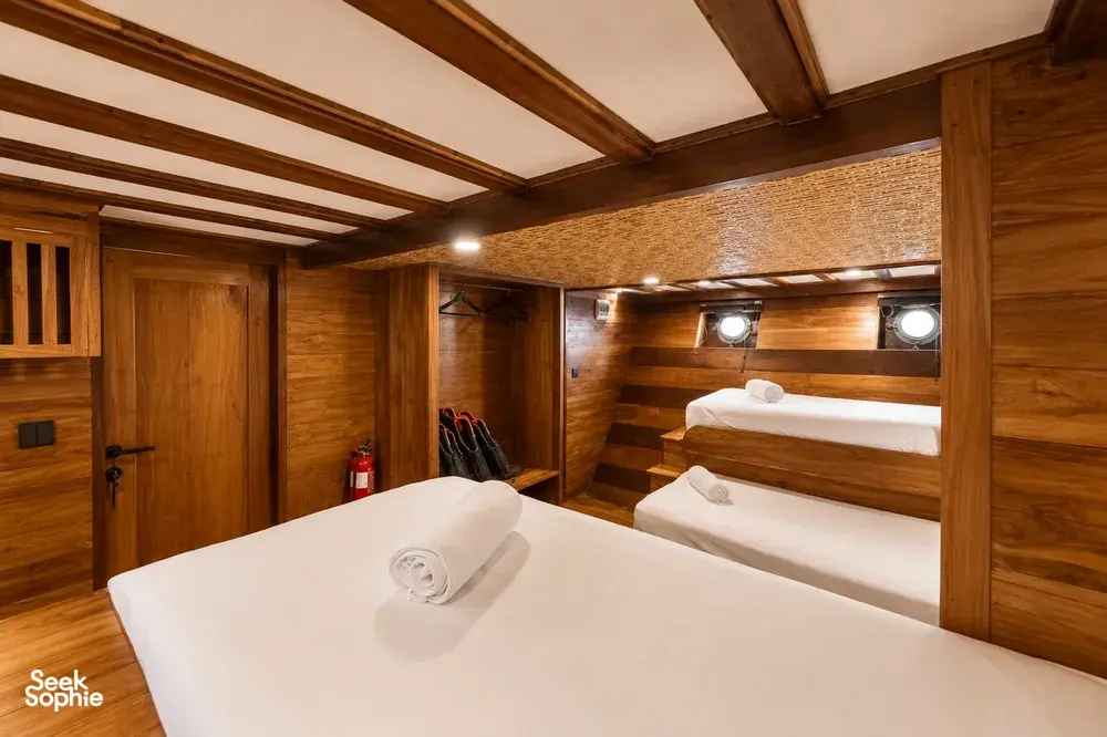 Travass Life phinisi cabin with two berths, rolled towels and warm wood-panelled walls, for a rare 3D2N shared trip on Komodo Island