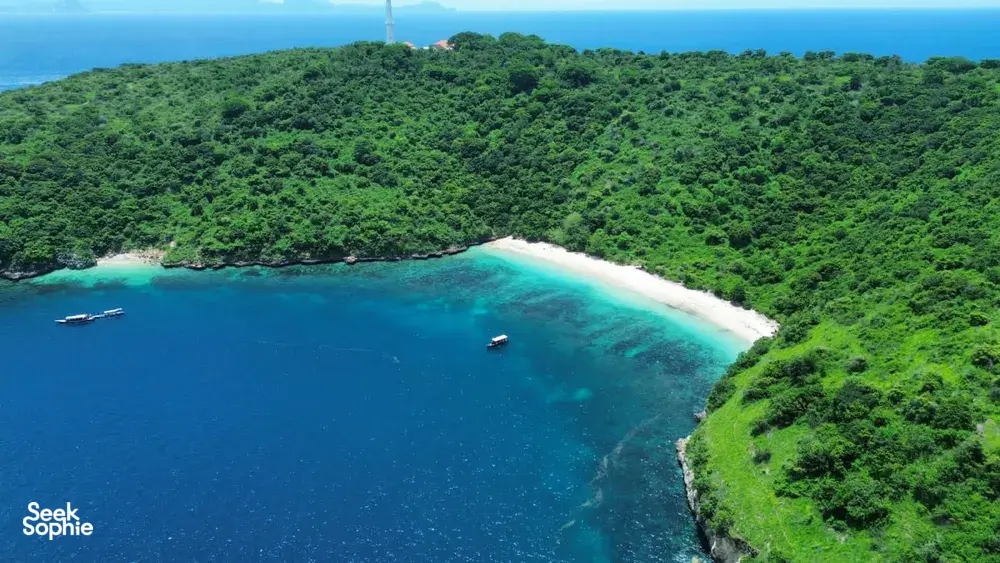 Aerial view of Lombok’s Pink Beach cove with clear turquoise water and small dive boats, on a Scuba Froggy fun dive trip