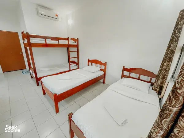 KOPEL Kinabatangan homestay bedroom in Sandakan with a bunk bed and two single beds, with folded towels, for a Kinabatangan River safari