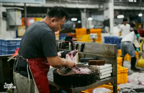 Seorang penjual ikan membersihkan seekor ikan besar di meja kerja logam di pasar ikan Pelabuhan Jurong, Singapura, sebelum memotongnya untuk dijual