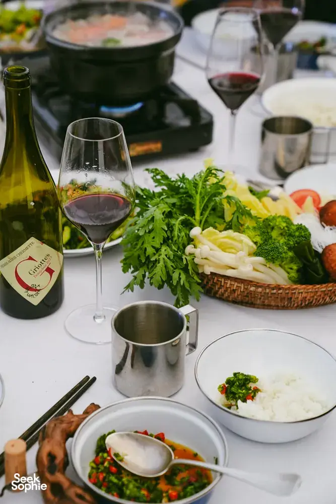Camp dining table set for a Shangri-La caravan journey, with wine, bowls of soup and fresh greens on white plates