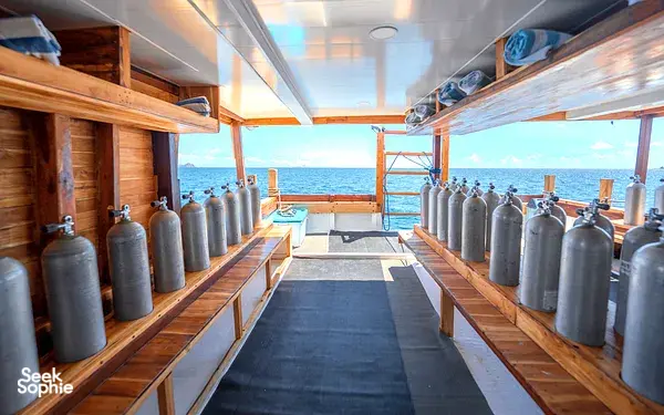 Row of metal scuba gas cylinders along a wooden corridor on a 4D3N Komodo dive liveaboard, ready for dives, Komodo Island