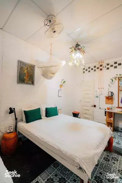 Mekong Delta pottery homestay bedroom with teal pillows, white brick walls, a chandelier light, and a small wash station