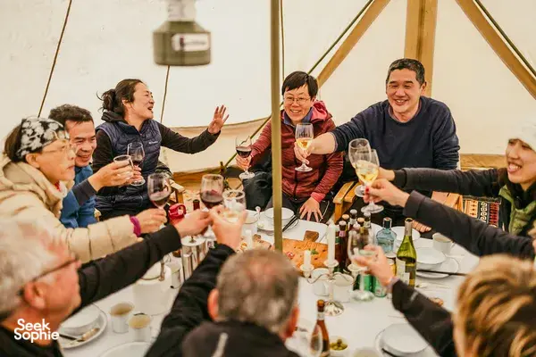 Group dining and toasting in a canvas dining tent during a nomadic caravan camp in Shangri-La’s remote valleys