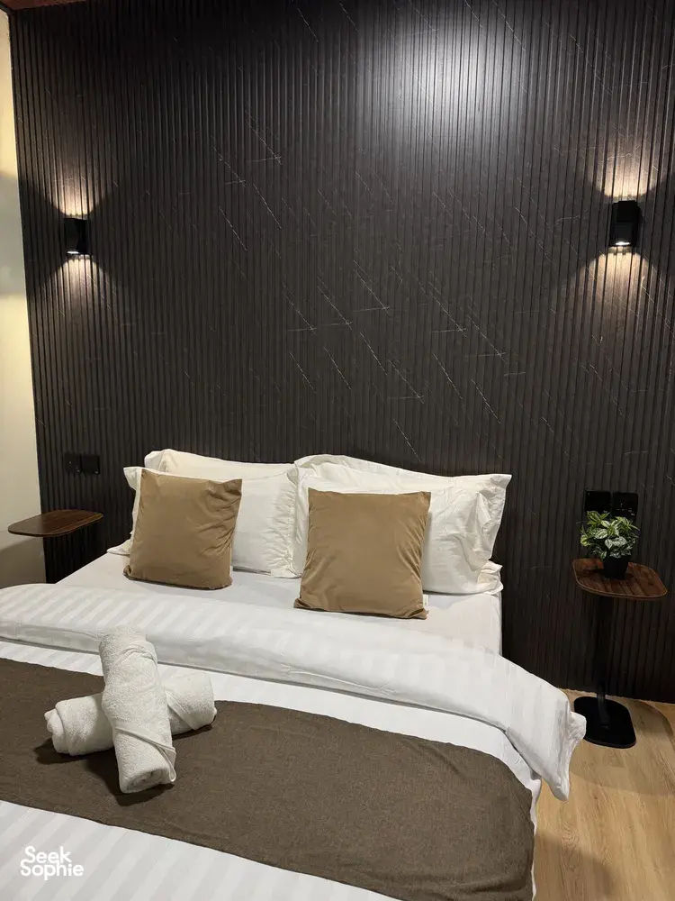 Made-up double bed with pillows and bedside lamps in a cosy guest room at Sukau Greenview Lodge, Kinabatangan River