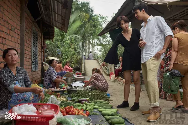 Local market lane with shoppers browsing piles of green beans, tomatoes and herbs in a Mekong Delta village