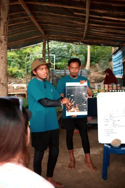Rinca Coral Nursery Program hosts presenting coral restoration notes to participants under a rustic shelter on Komodo Island